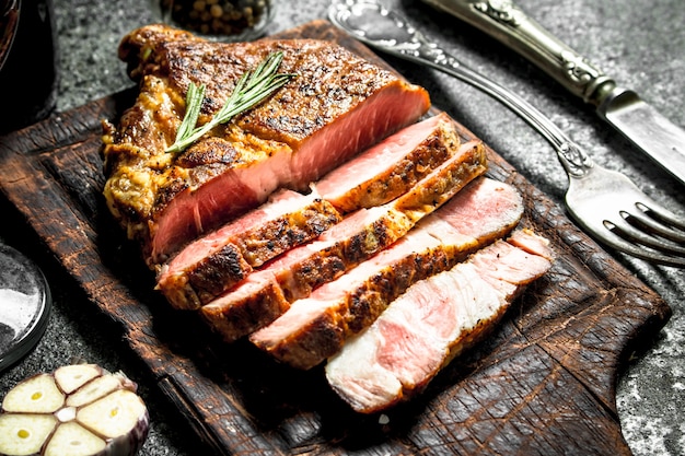 Grilled beef steak on a blackboard with spices. On rustic background.