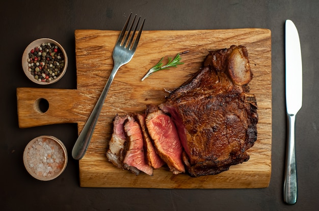 grilled beef steak on a cutting board on a stone background