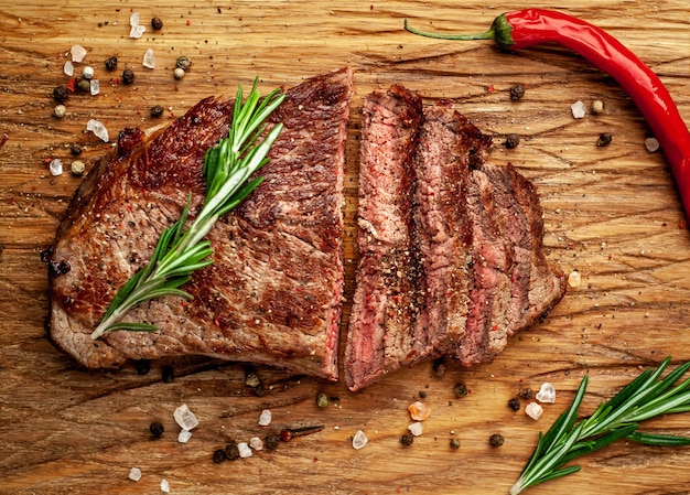 grilled beef steak on a cutting board with spices on a stone background