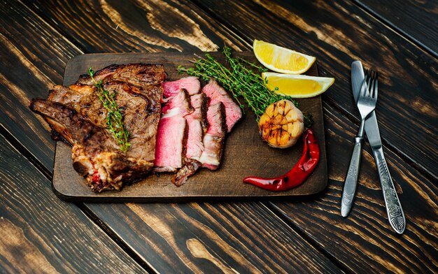 grilled beef steak on cutting board on wood background