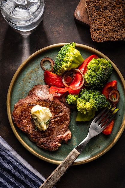 Grilled Beef steak with garlic butter and vegetables. Meat with grilled bell pepper, broccoli and onions.