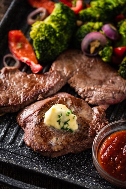 Bistecca di manzo alla griglia con burro all'aglio e verdure. carne con peperoni grigliati, broccoli e cipolle.