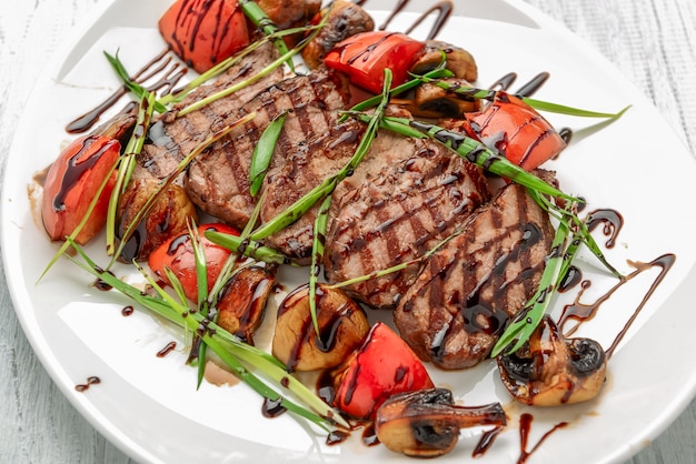 Foto bistecca di manzo alla griglia con funghi e pomodori