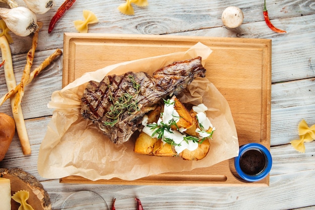 Grilled beef steak with potatoes on wooden board