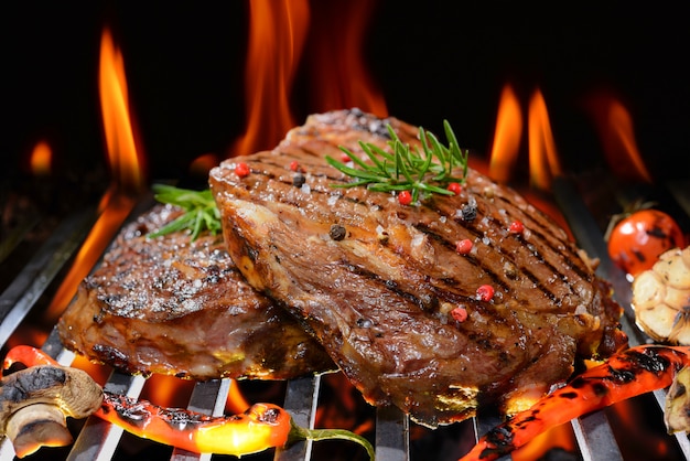Photo grilled beef steak with vegetable on the flaming grill