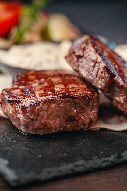 灰色のスレート背景に野菜と牛肉のグリルステーキ