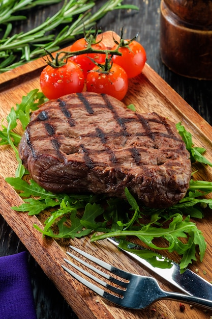 Grilled beef steak on wooden cutting board.