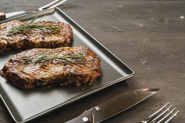 Grilled Beef steaks served with rosemary on  metal tray, close up