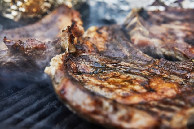 Foto bistecche di manzo alla griglia con fumo alla griglia. festa barbecue.