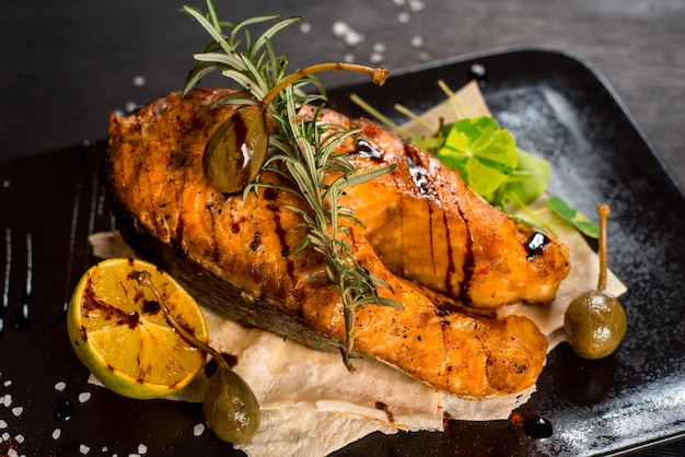 Grilled big fish steak on the black wooden background