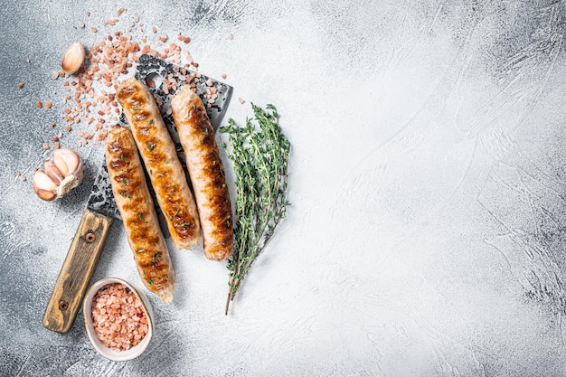 Grilled Bockwurst and Bratwurst meat sausages on a cleaver. White background. Top view. Copy space.