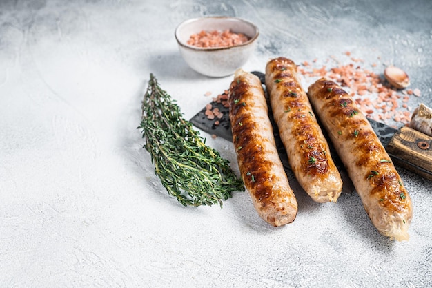 Жареные мясные колбаски Bockwurst и Bratwurst на тесаке. Белый фон. Вид сверху. Скопируйте пространство.