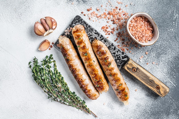 Grilled Bockwurst and Bratwurst meat sausages on a cleaver. White background. Top view.