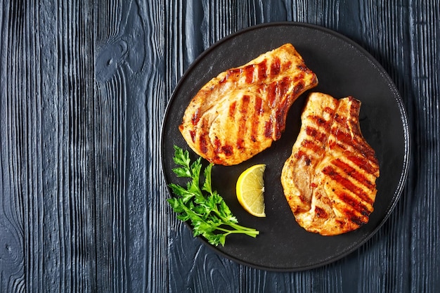 Grilled bonein pork chops on a black plate