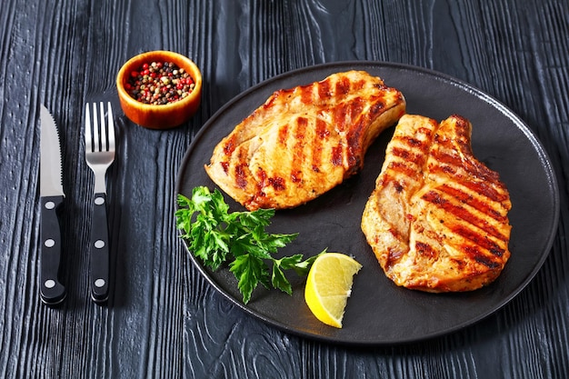 Grilled bonein pork chops on a black plate