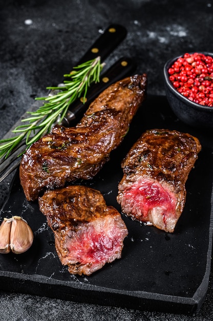 Grilled brisket steaks in bbq sauce on a marble board on wooden table. Top view.