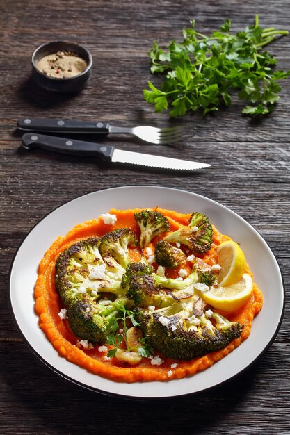 Grilled broccoli steak with pumpkin mash topped  with crumbled feta cheese, vegetarian recipe, vertical view from above