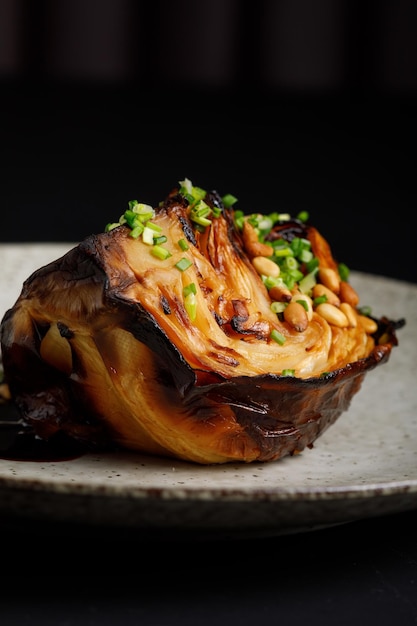 Grilled cabbage served with sauce and pine nuts Delicious vegetarian food Dark moody style