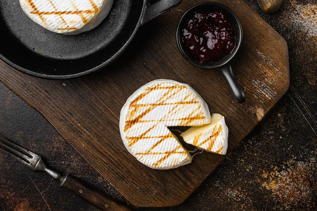 Grilled camembert or brie cheese on old dark rustic table background top view flat lay