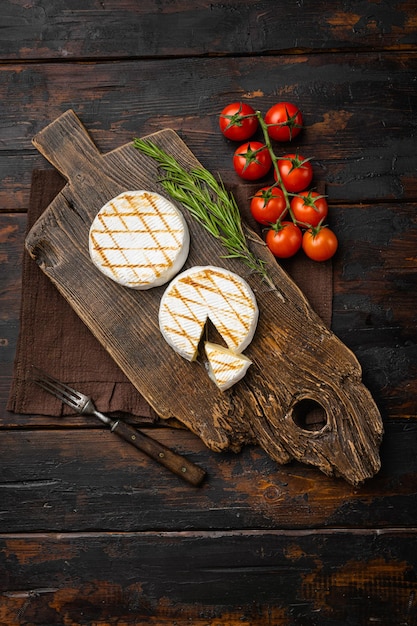 Grilled camembert or brie cheese on old dark wooden table background top view flat lay with copy space for text