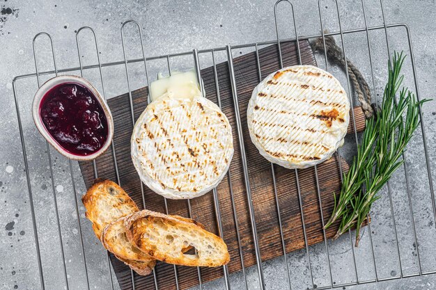 Grilled Camembert cheese on grill with cranberry sauce and toast Gray background Top view