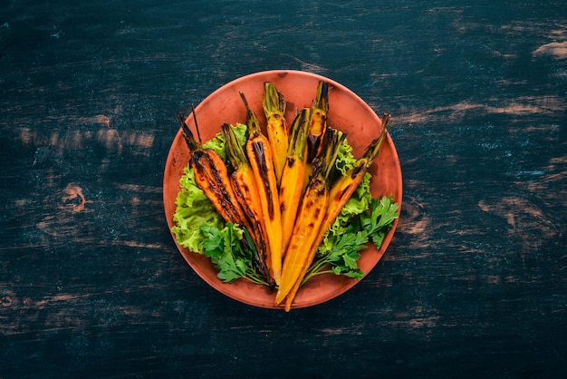 Grilled carrot in a plate with vegetables On a wooden background Top view Copy space