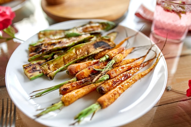 Grilled carrots and zucchini on plate on the dinner table, appetizers variety serving on party outdoor table at home.