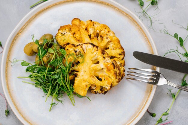 Grilled cauliflower dish with olives and microgreens Vegan menu