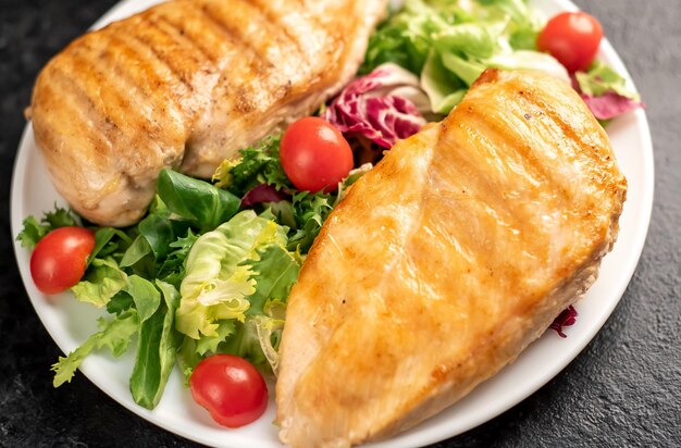 grilled chicken breast and cherry tomato salad on stone background