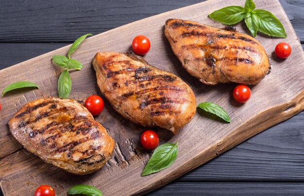 Grilled chicken breast fillet with basil and tomatoes BBQ background