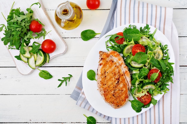 Petto di pollo alla griglia e insalata di verdure fresche - pomodori, cetrioli e foglie di lattuga. insalata di pollo. cibo salutare. disteso.