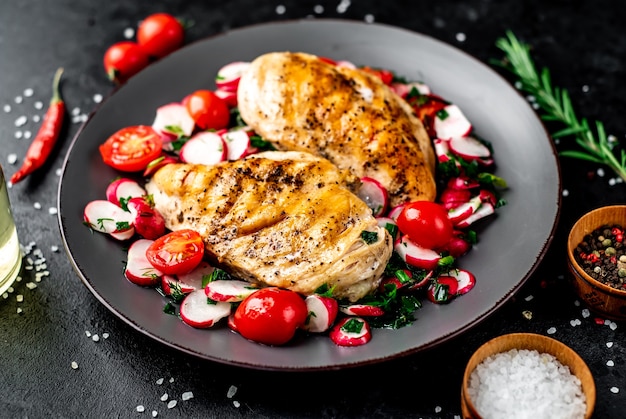 Grilled chicken breast and salad with fresh vegetables tomatoes and radishes in a plate Chicken meat with salad Healthy food on stone table