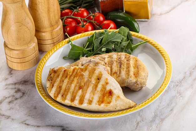 Grilled chicken breast served arugula and tomatoes