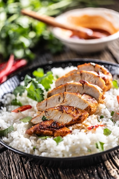 Grilled chicken breast served in a pan with jasmine rice and chili peppers