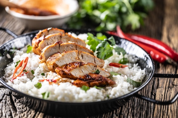 Photo grilled chicken breast served in a pan with jasmine rice and chili peppers