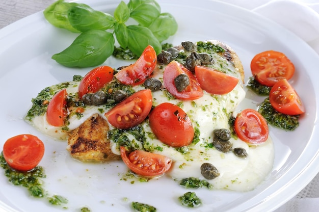 Grilled chicken breast  topped with melted mozzarella cheese basil  pesto tomato  and caper