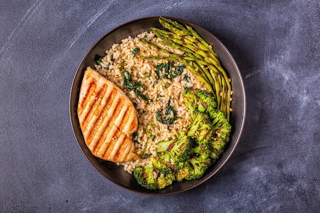 Grilled chicken breast with brown rice, spinach, broccoli, asparagus, concept of diet, healthy eating.