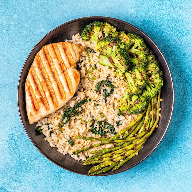 Petto di pollo alla griglia con riso integrale, spinaci, broccoli, asparagi, concetto di dieta, mangiare sano.