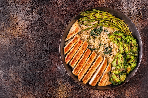 Grilled chicken breast with brown rice, spinach, broccoli, asparagus, concept of diet, healthy eating.