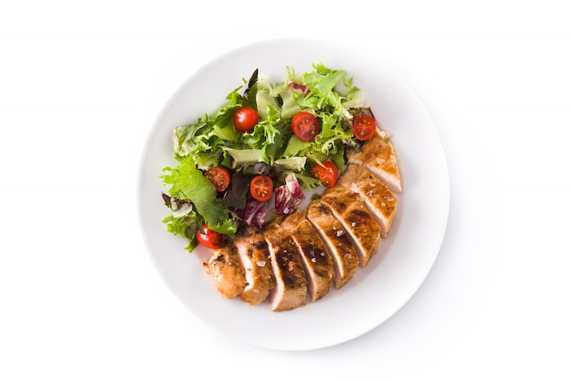 Grilled chicken breast with vegetables on a plate isolated