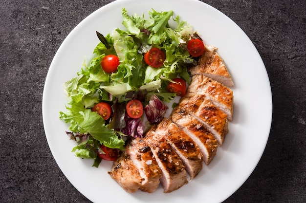 Grilled chicken breast with vegetables on a plate. Top view.