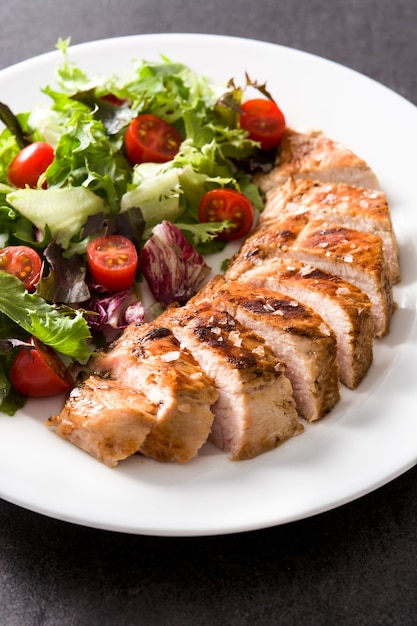 Grilled chicken breast with vegetables on a plate.