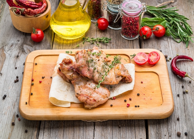 Grilled chicken breast on a wooden board with tomatoes and mushrooms