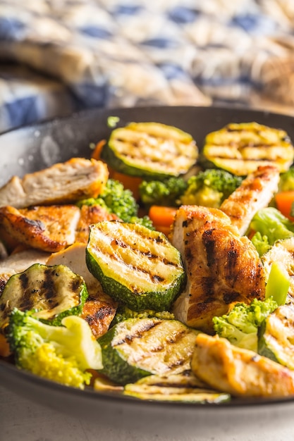 Grilled chicken breast zucchini broccoli and carrot in black plate. Greek or mediterranean food.