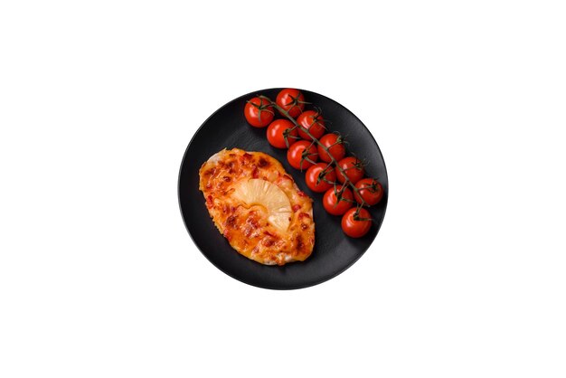 暗いコンクリートの背景にトマト パイナップルとチーズを添えたステーキの形のグリル チキン フィレ
