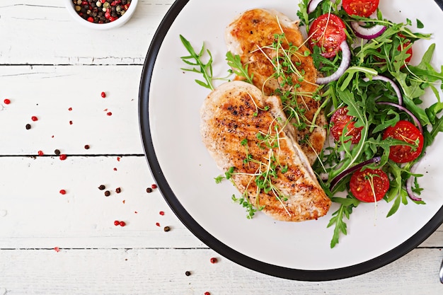 Grilled chicken fillet and fresh vegetable salad of tomatoes,red onion and arugula