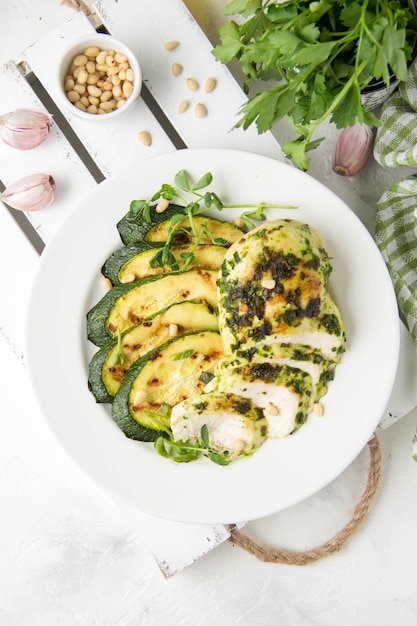 Grilled chicken fillet with green herb marinade, with slices of fried zucchini and pine nuts