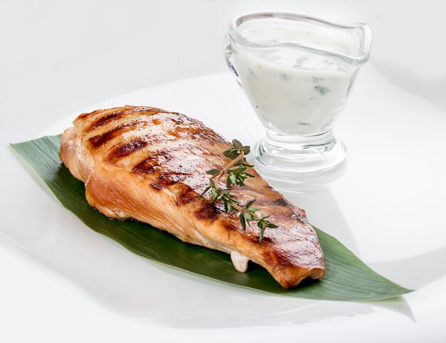 Grilled chicken fillet with sauce on white background