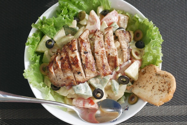 Grilled chicken and fresh vegetable salad on table