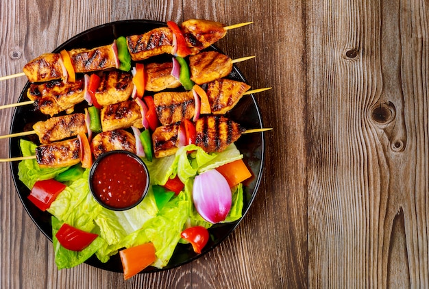 Grilled chicken kebab on wooden skewer with sauce